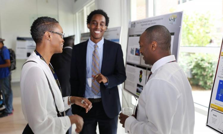 Three people discuss a research poster at a poster session.