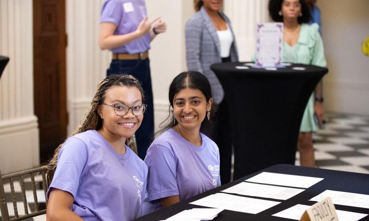 Two SWE members smile at the Tea with the Dean registration table.