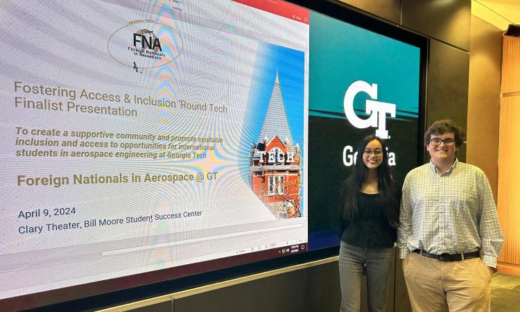 Two members of the winning FAIR Tech competition team, Jasrayman “Ray” Thind and Alfonso Lagares de Toledo, stand at a screen displaying the title slide of their final presentation.