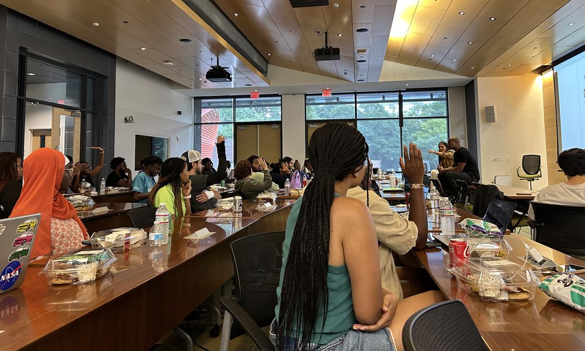 Students raise their hands to ask DJ Lewis questions at his "Young, Dumb & Broke" workshop